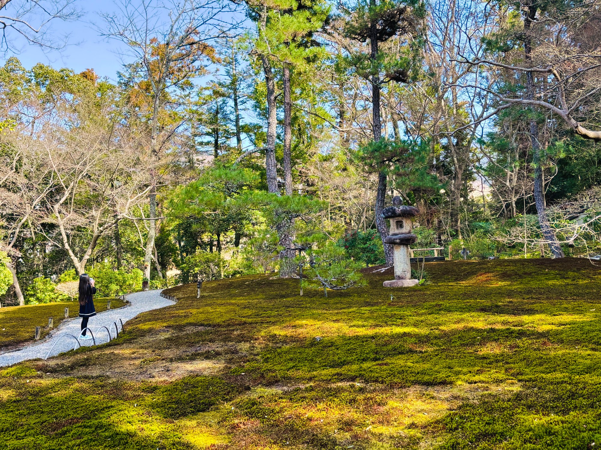 吉城園の苔の庭と大きな石灯籠。小道で娘が写真を撮っている