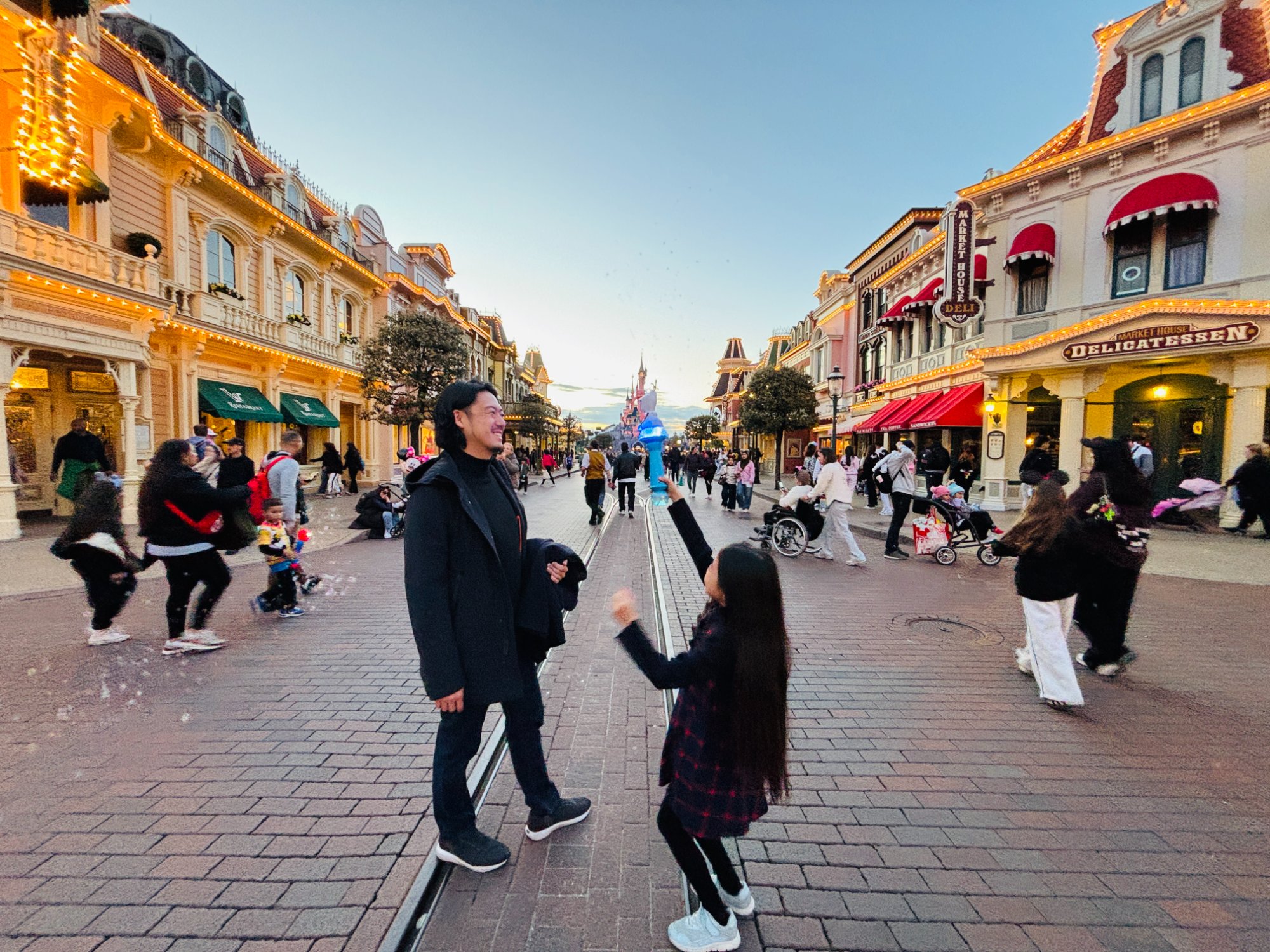 夕暮れの Main Street, U.S.A. で向かい合う父と娘。奥に眠れる森の美女の城