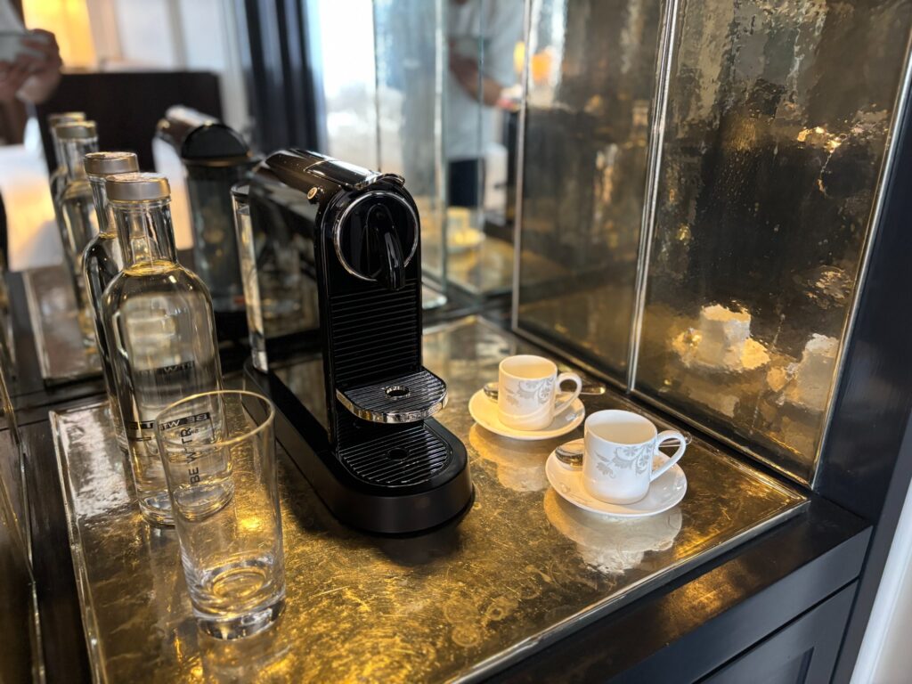 部屋に置かれたコーヒーマシンとカップ、水のボトル